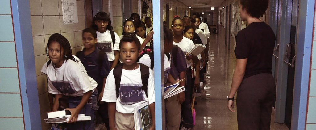 Students lined up outside classroom in hallway.