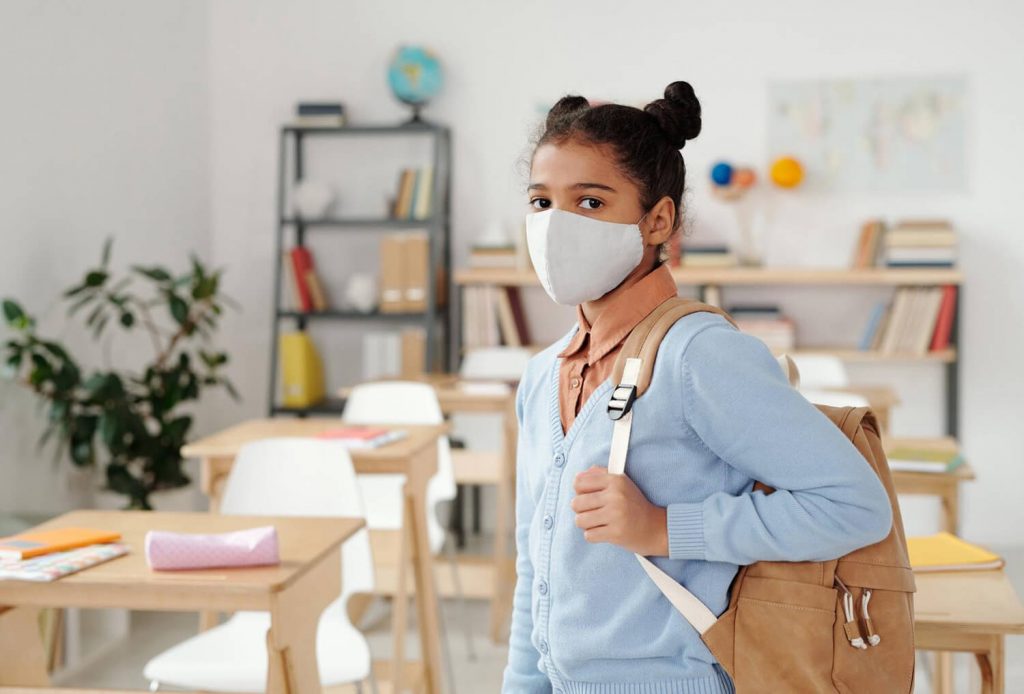 Child with school bag and face mask on.