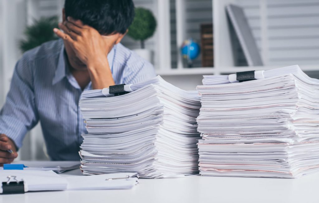 person behind a stack of papers on a desk