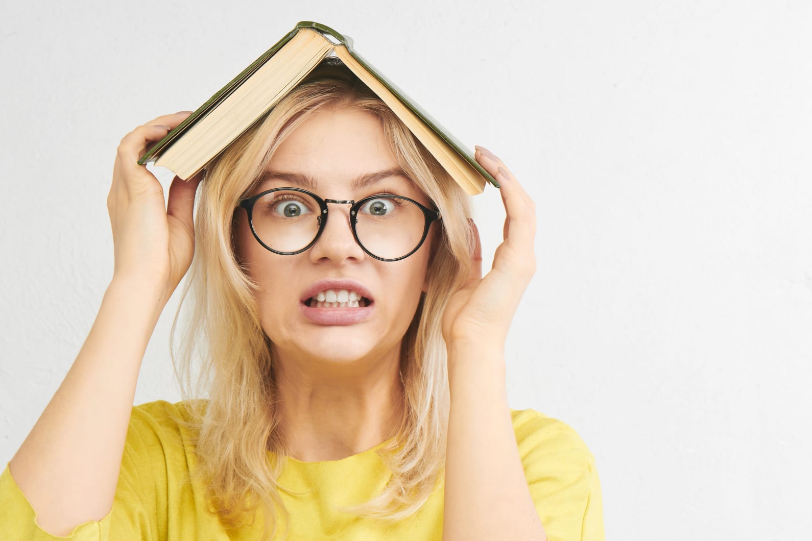Frustrated student holding open book over head